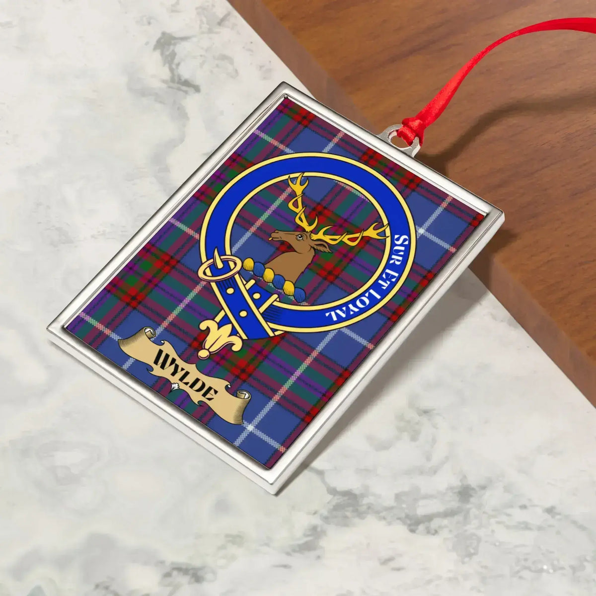 Wylde ornament hanging from a Christmas tree branch by its satin ribbon