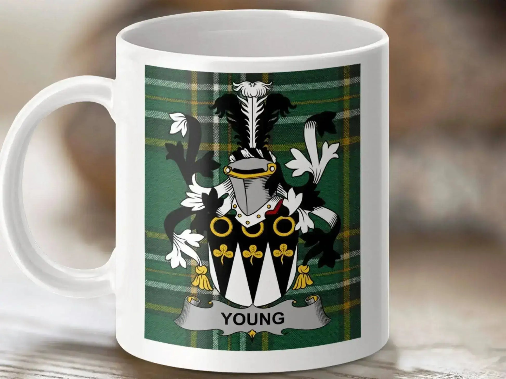 White ceramic mug featuring Young family crest with shield and helmet on green tartan background