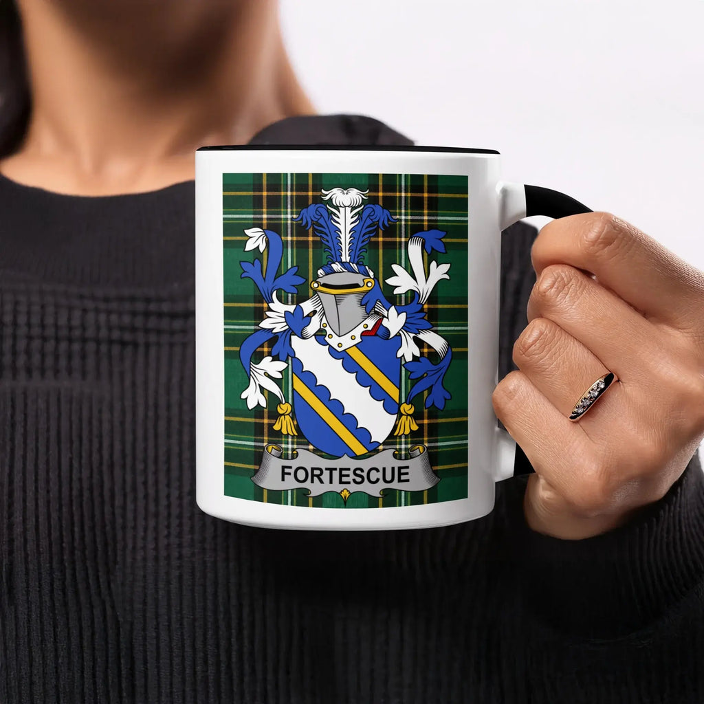 Black mug with Fortescue family crest on a plaid background.