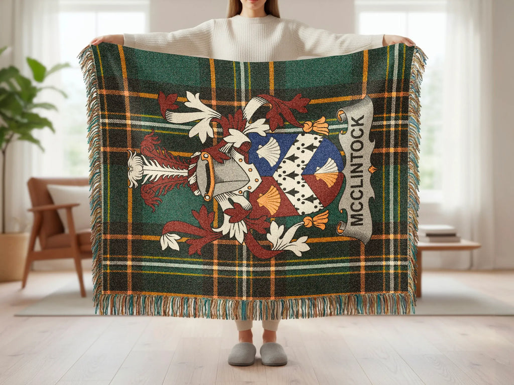 Tartan throw blanket with McClintock family crest held by a person.