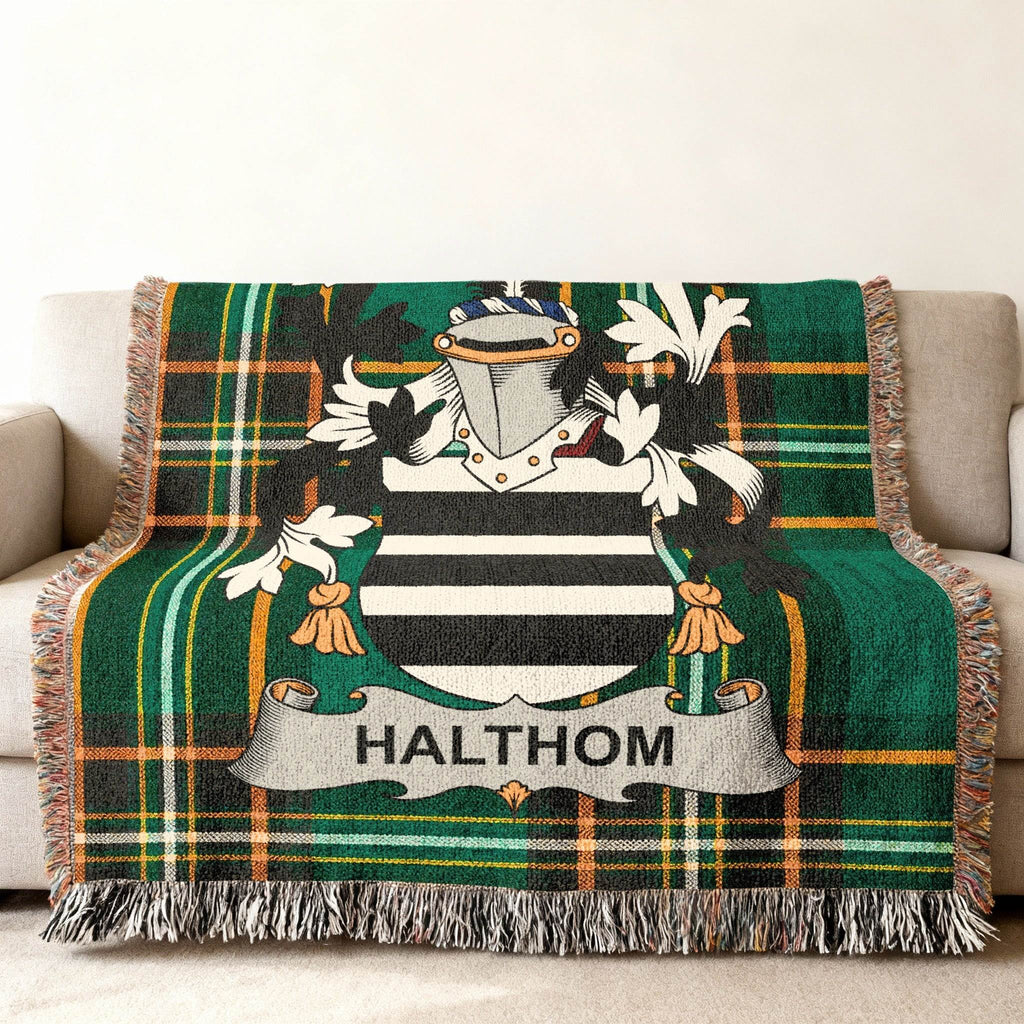 Green plaid throw blanket with a coat of arms and "HALTHOM" text.