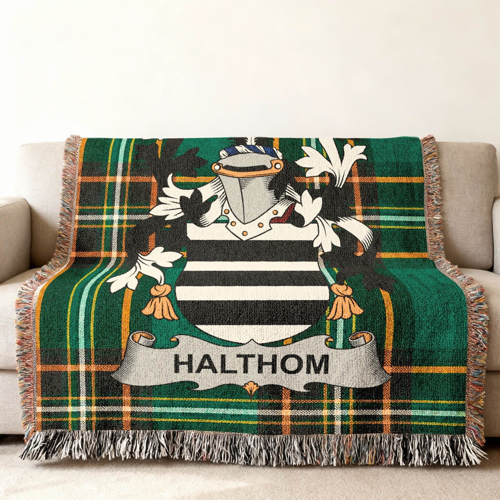 Green plaid throw blanket with a coat of arms and "HALTHOM" text.