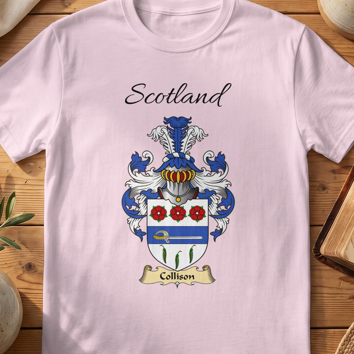 Light Pink Collison Scottish family shield T-shirt featuring red flowers above a blue band and green leaf motifs