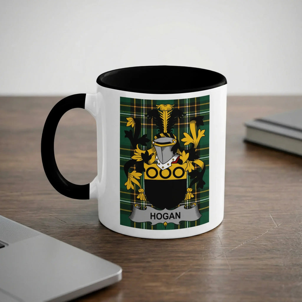 White mug with black rim featuring the Hogan family crest on a dark green plaid background.
