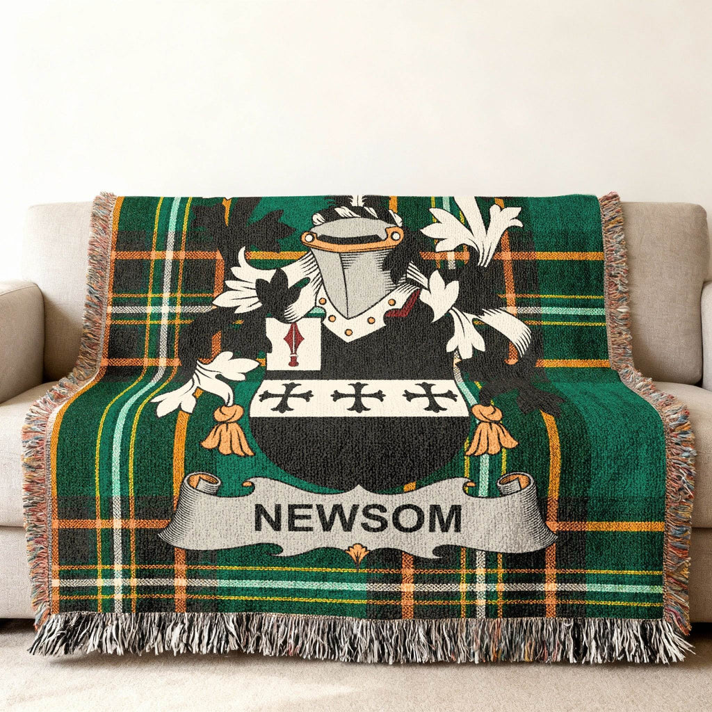 Newsom family crest on a green and black plaid woven blanket draped on a sofa.
