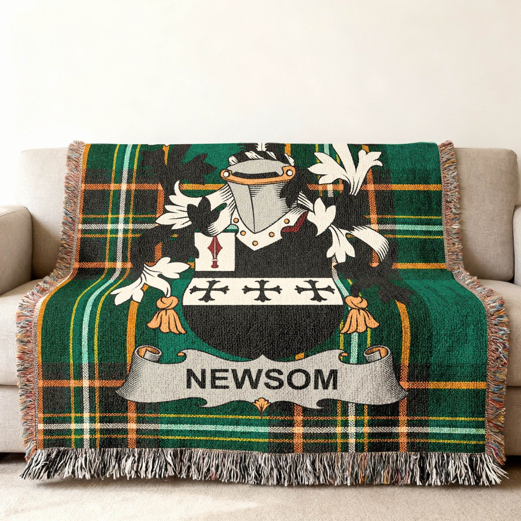Newsom family crest on a green and black plaid woven blanket draped on a sofa.