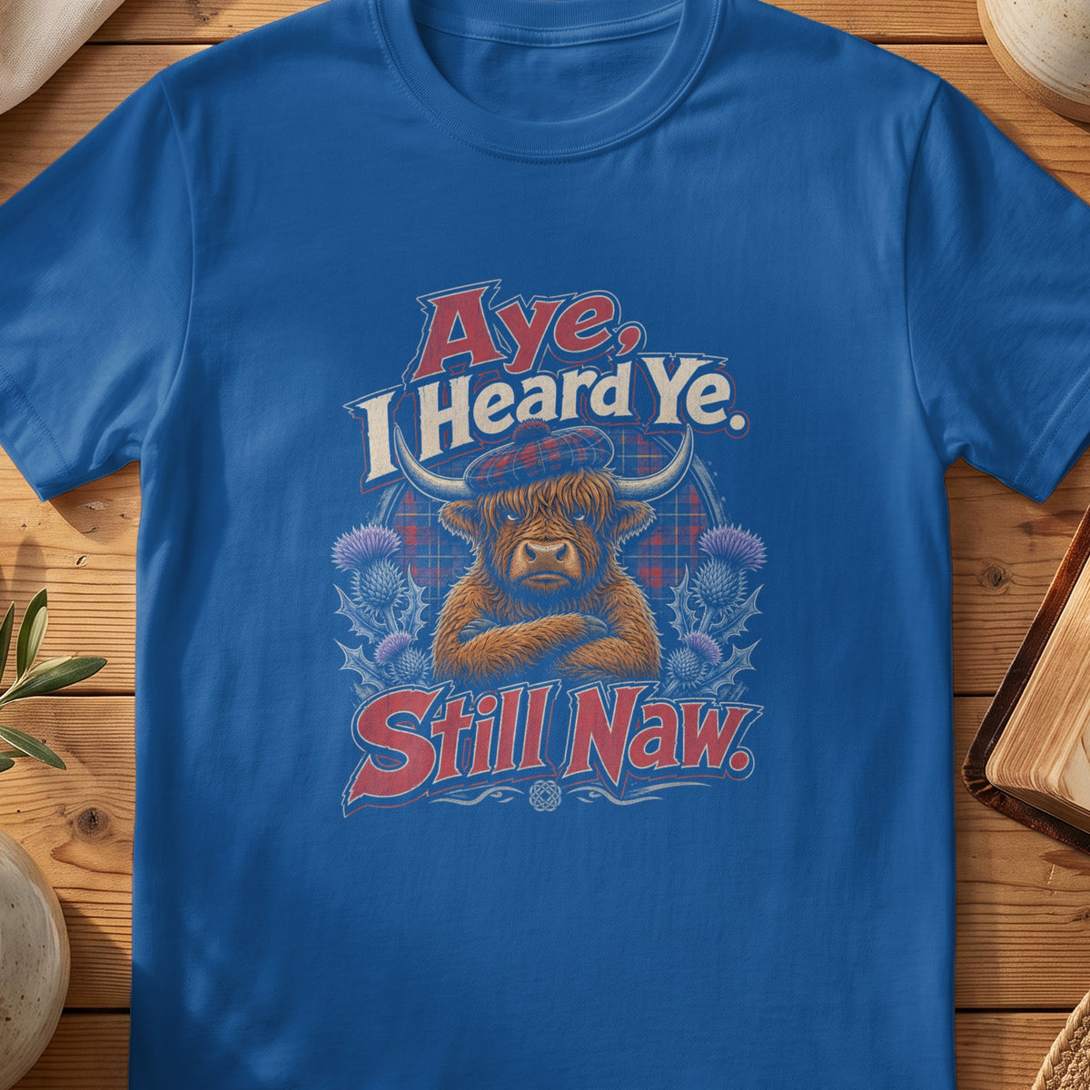 Highland cow wearing a tartan beret with text "Aye, I Heard Ye. Still Naw."