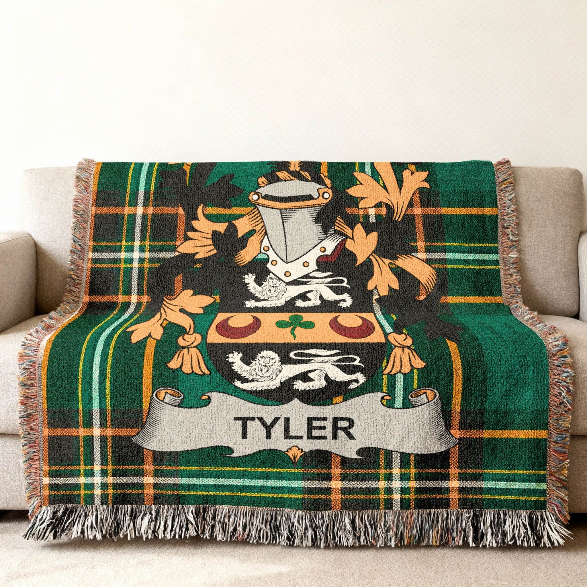 Green plaid blanket with the Tyler family crest and fringe on a sofa.