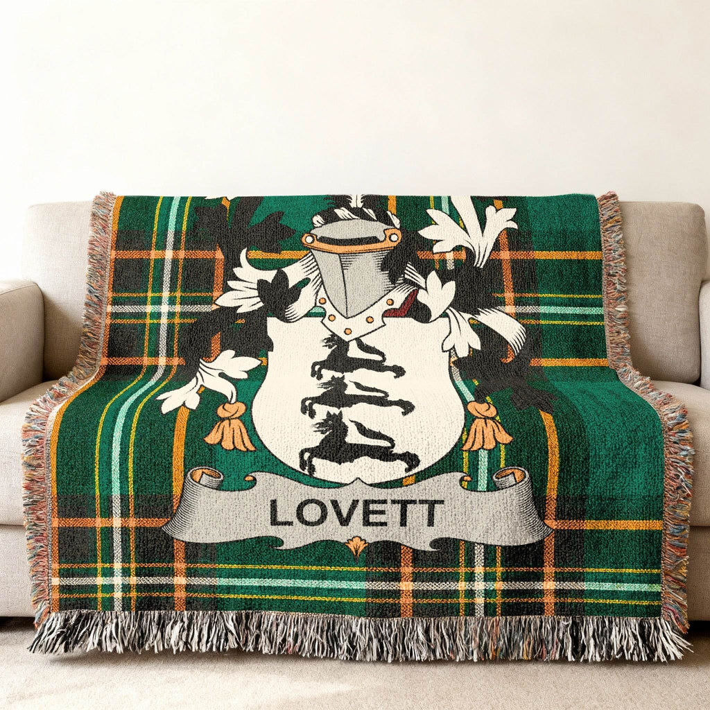 Green plaid woven blanket with Lovett family crest on a couch.