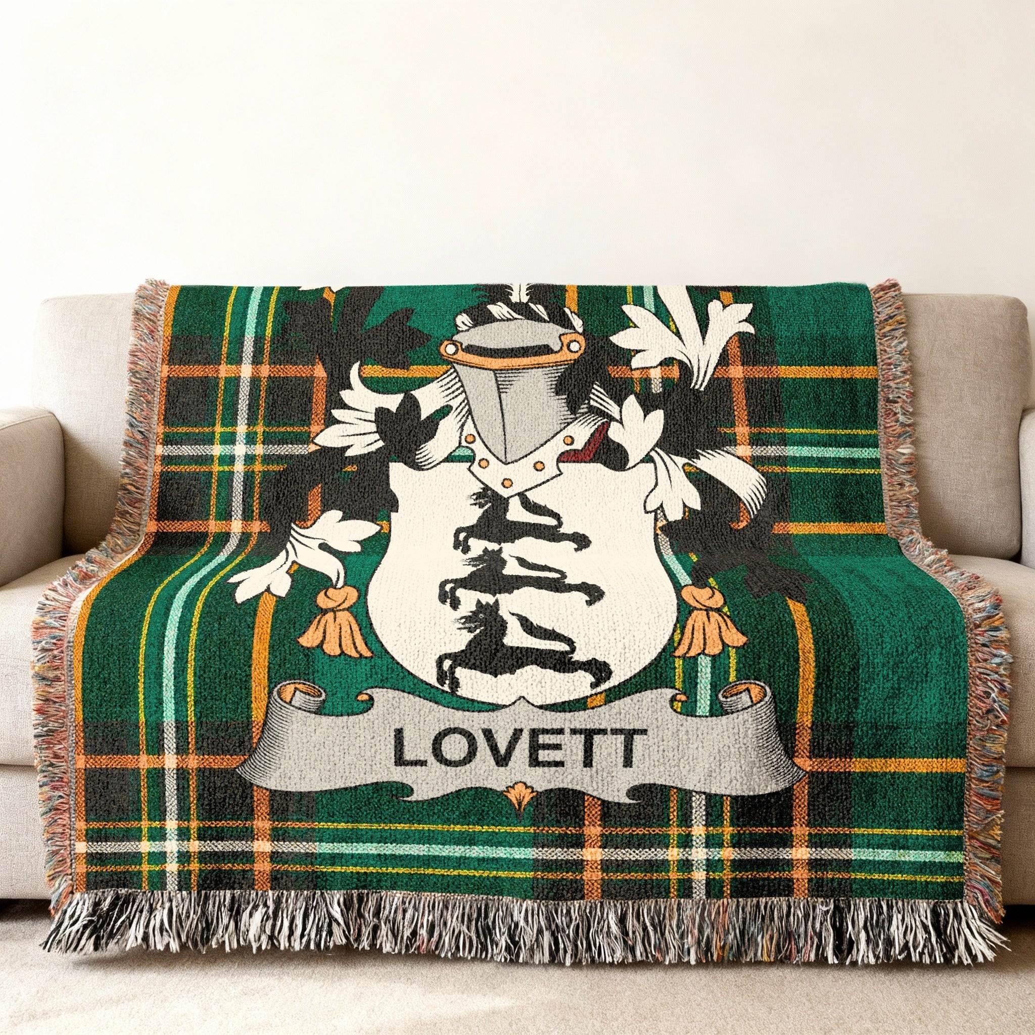 Green plaid woven blanket with Lovett family crest on a couch.