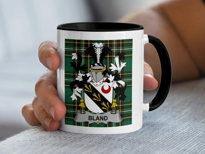 White mug with black handle featuring a green tartan plaid and a coat of arms with the name "BLAND".