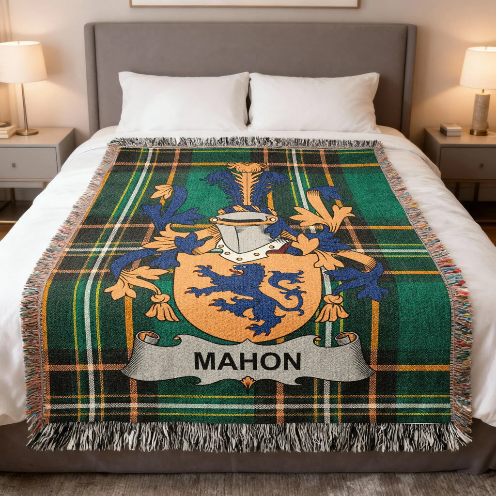 Green tartan plaid blanket with Mahon family crest on a bed.