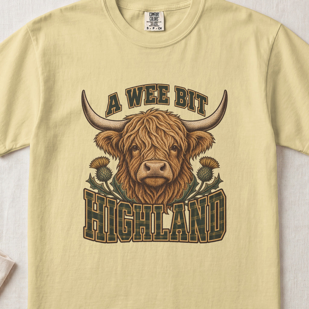 A Wee Bit Highland Highland cow design on a Butter Comfort Colors 1717 T-shirt, flat lay