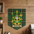 Sweeney family crest banner hanging on a wooden wall, featuring green plaid.