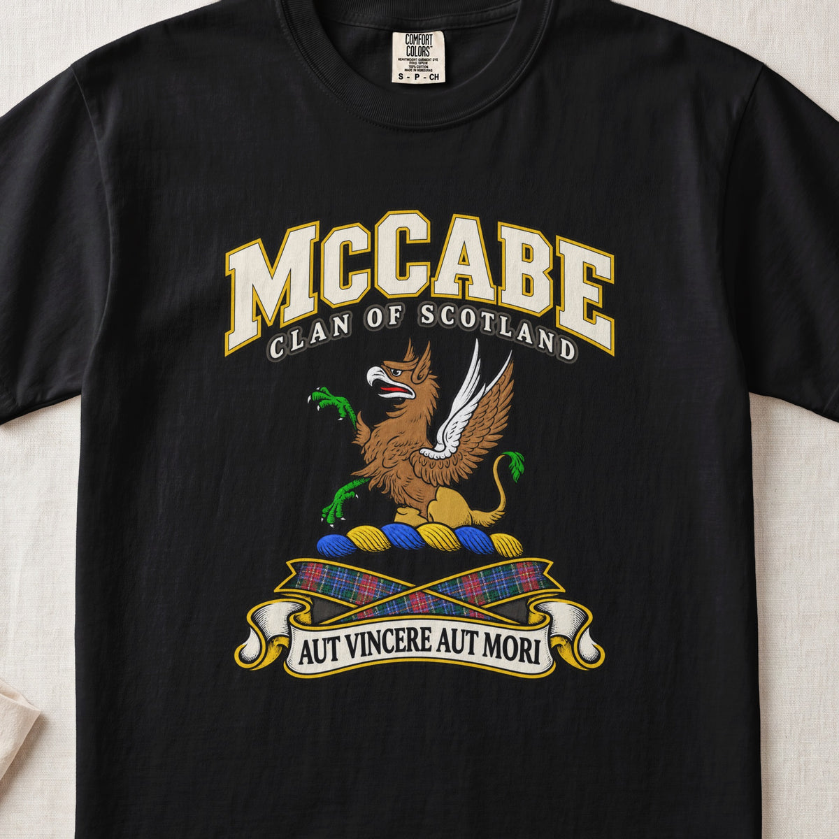 McCabe Scottish clan T-shirt in Black, front view with a brown and gold winged griffin with green claws and motto banner.