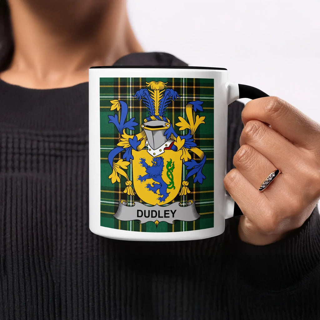 Black mug with Dudley family crest on a plaid background.