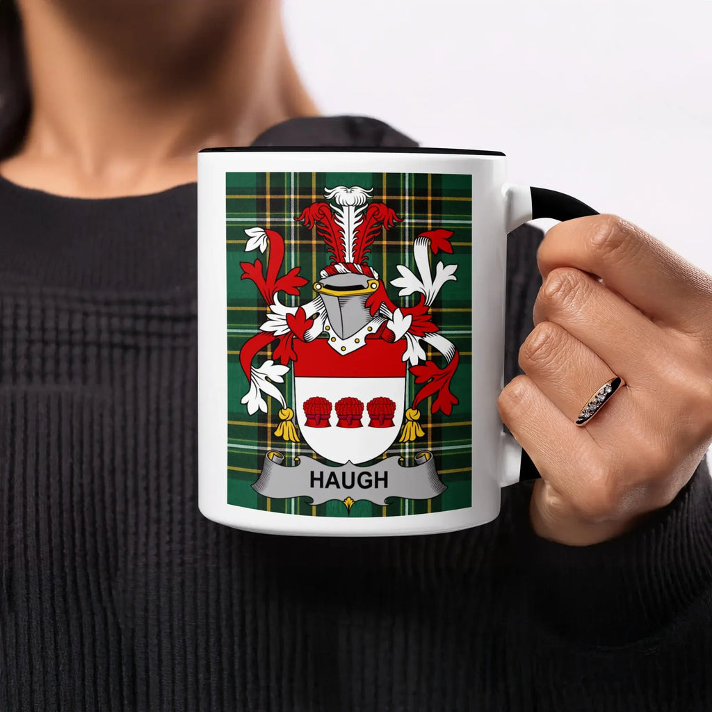 White mug with Haugh family crest on green tartan background.