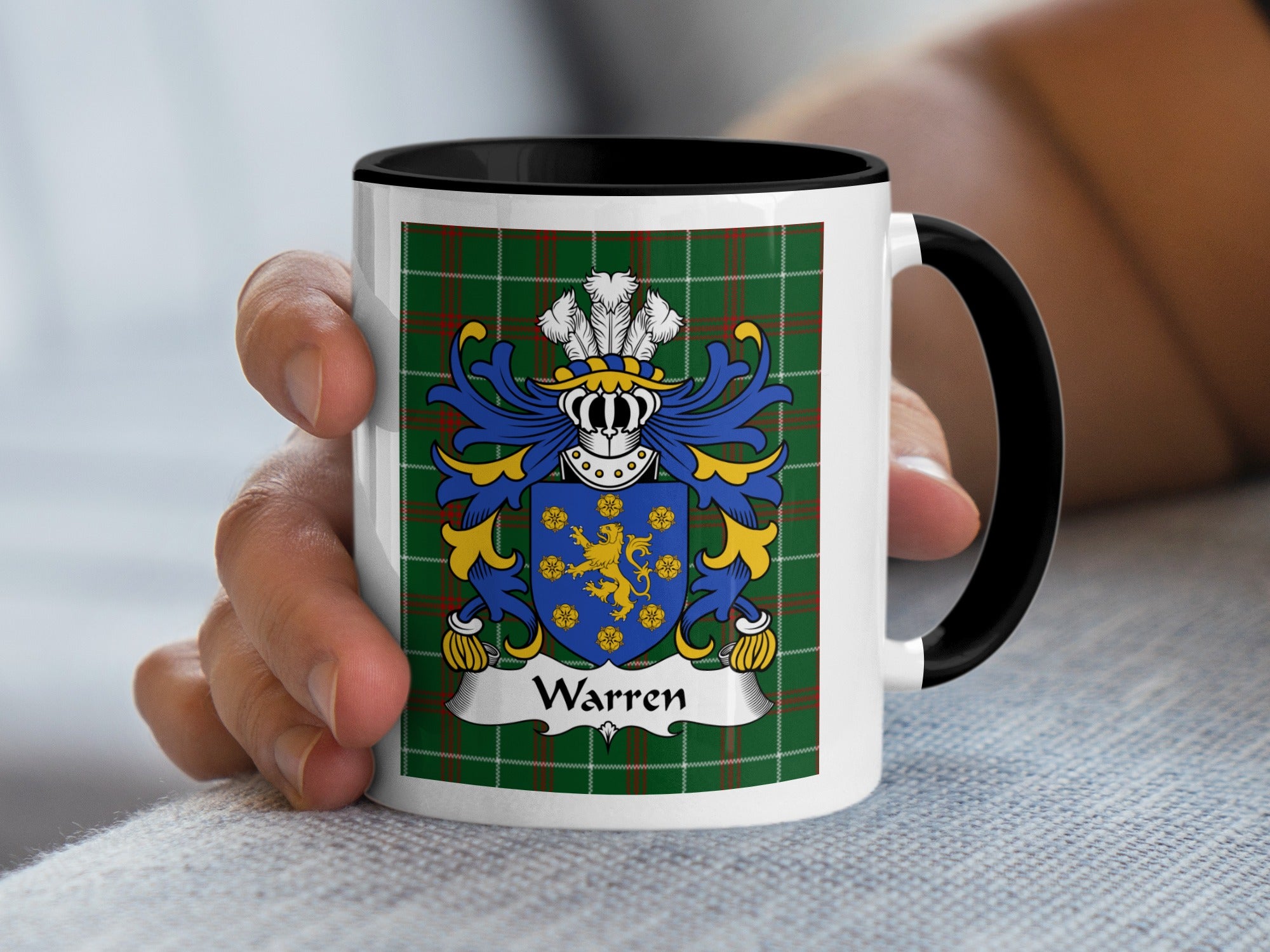 Mug with Warren family crest on green tartan background held by hand.