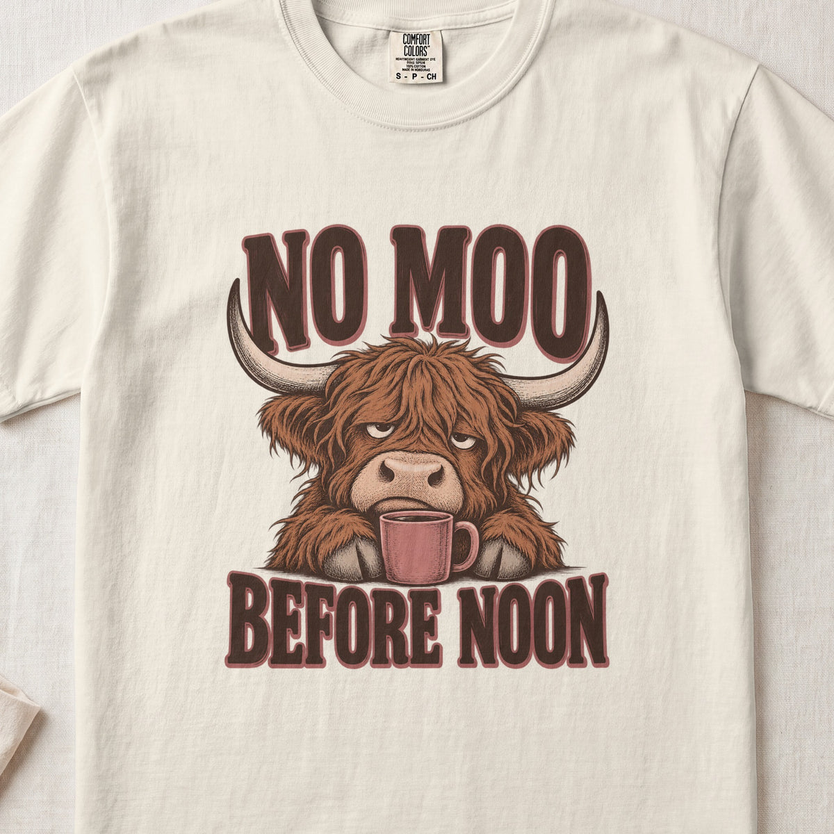 No Moo Before Noon Highland cow design on an Ivory Comfort Colors 1717 T-shirt, flat lay