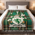 Green and black plaid blanket with Holmes family crest on a bed.