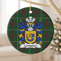 Langston ceramic ornament hanging from a pale wooden branch, showing a gold shield with a blue hunting horn and looped cord on Welsh national tartan.
