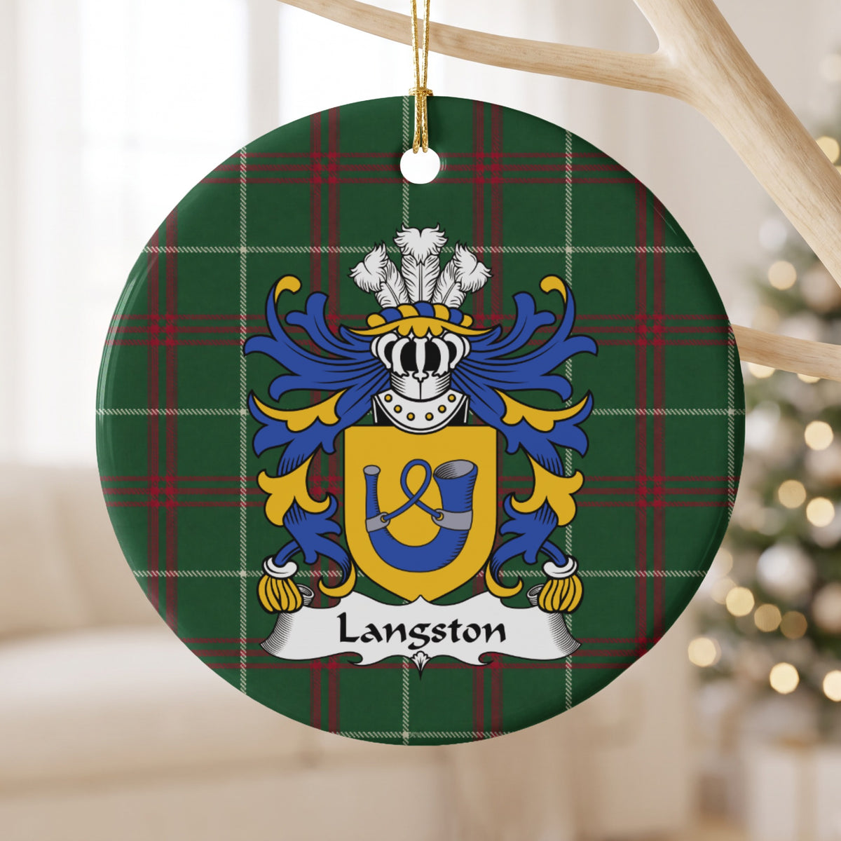Langston ceramic ornament hanging from a pale wooden branch, showing a gold shield with a blue hunting horn and looped cord on Welsh national tartan.