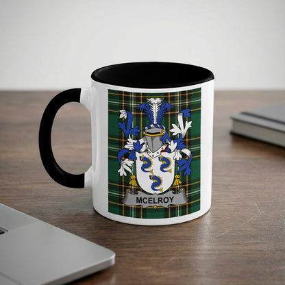 White mug with black handle featuring a green, blue, and yellow McElroy family crest.
