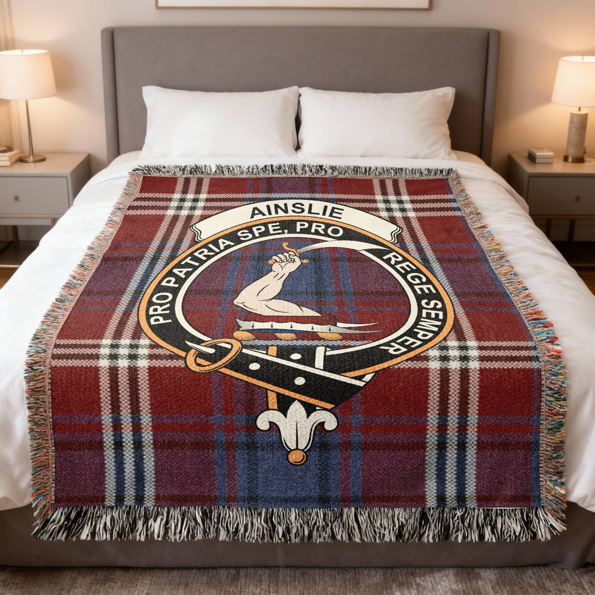 Ainslie woven blanket displayed on a bed, with an arm holding a curved sword on a red, blue and cream tartan background