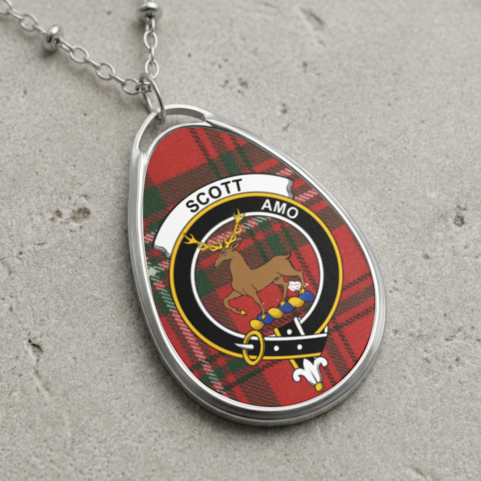 Oval pendant necklace with Scott clan crest on red tartan.