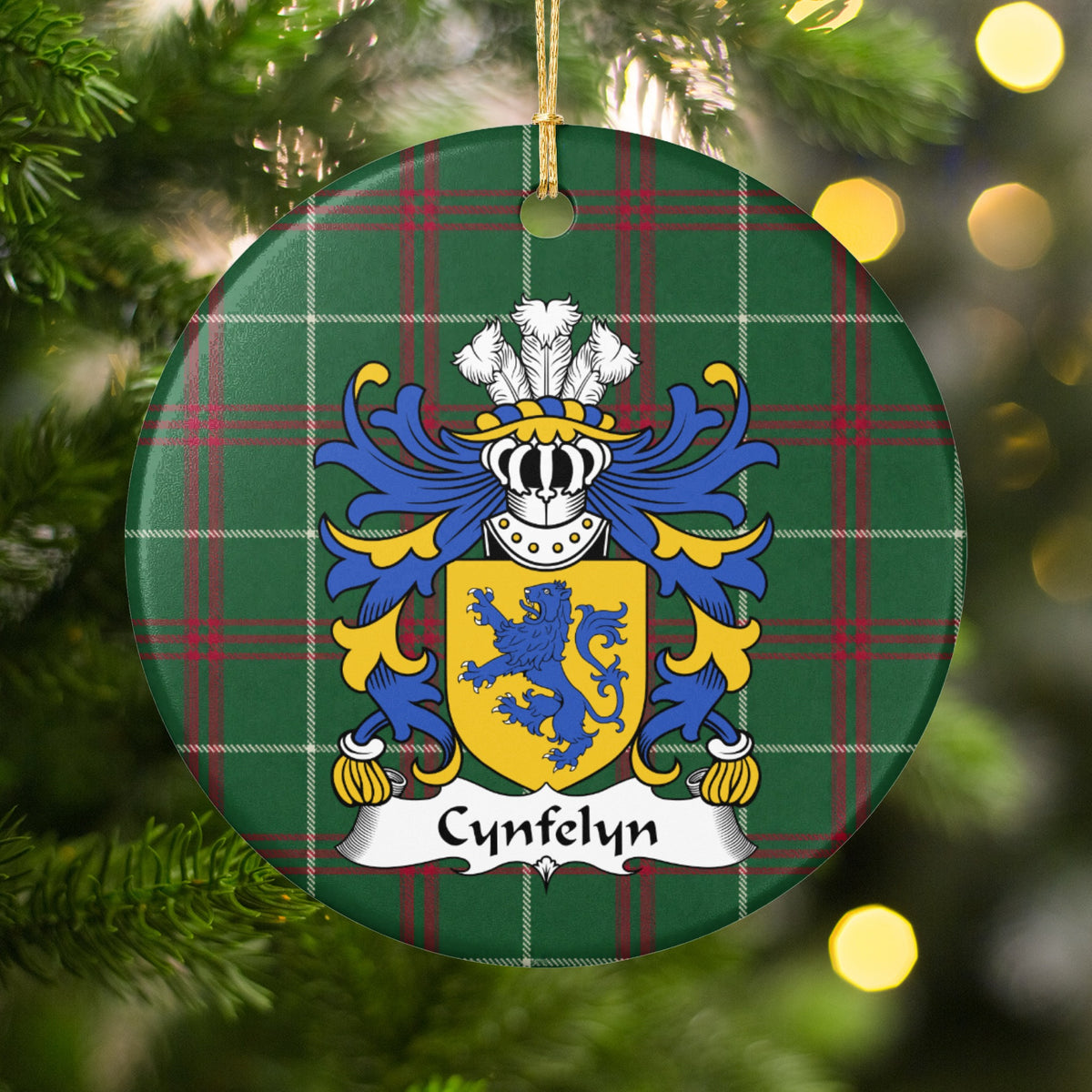Cynfelyn ornament hanging among Christmas tree branches and warm lights; a blue upright lion on a gold shield on Welsh national tartan.