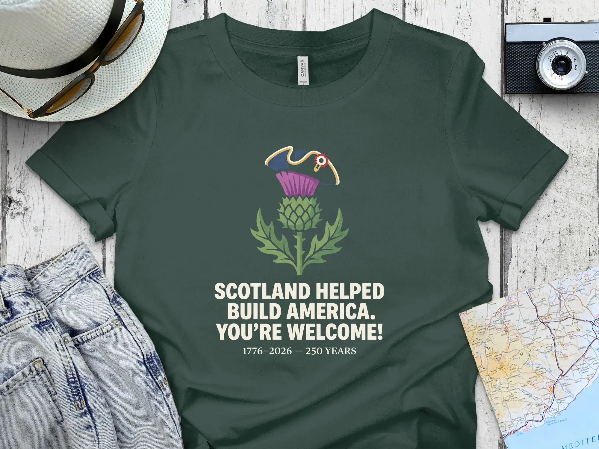 Dark green t-shirt with Scottish thistle and "Scotland Helped Build America" text.