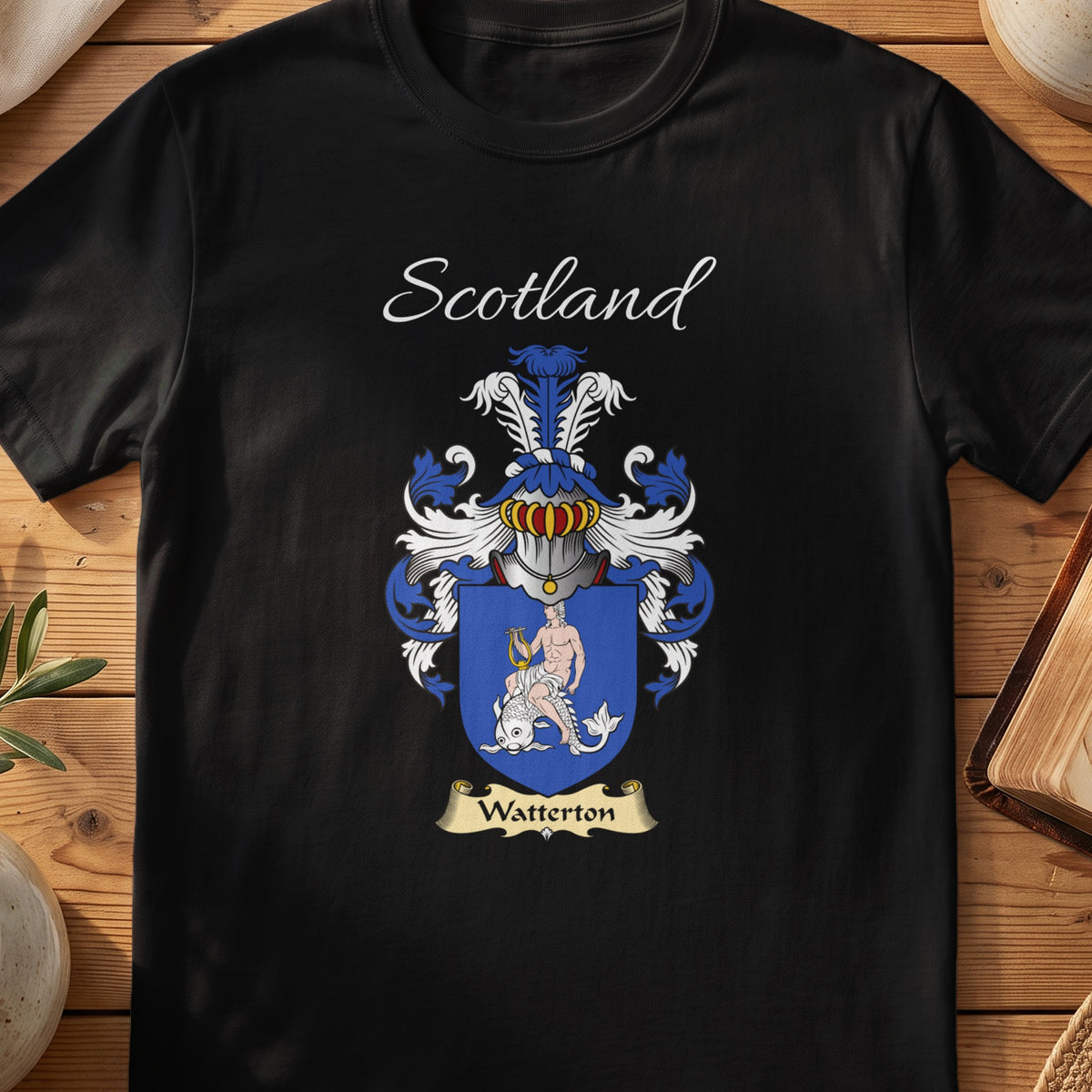 Black Watterton Scottish family crest T-shirt laid flat, showing “Scotland” above a blue-and-silver shield carrying a detailed animal figure.