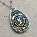 Napier Sans Tache crest pendant on silver chain with blue tartan background.