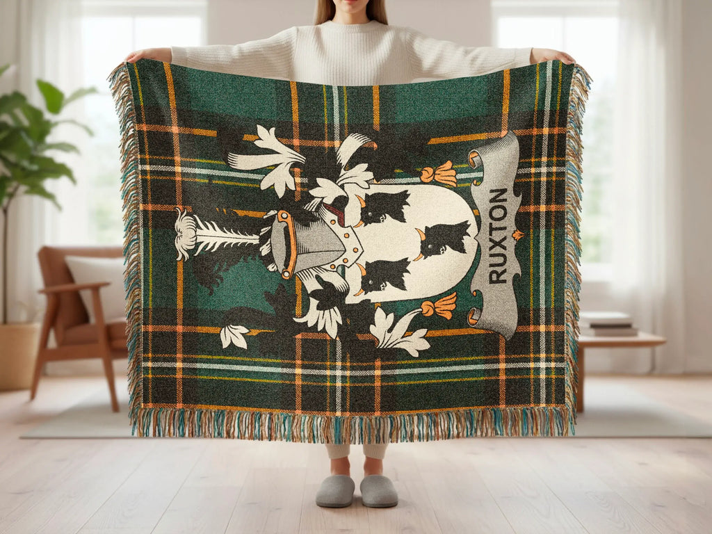 Ruxton tartan blanket with crest, held up by a person.