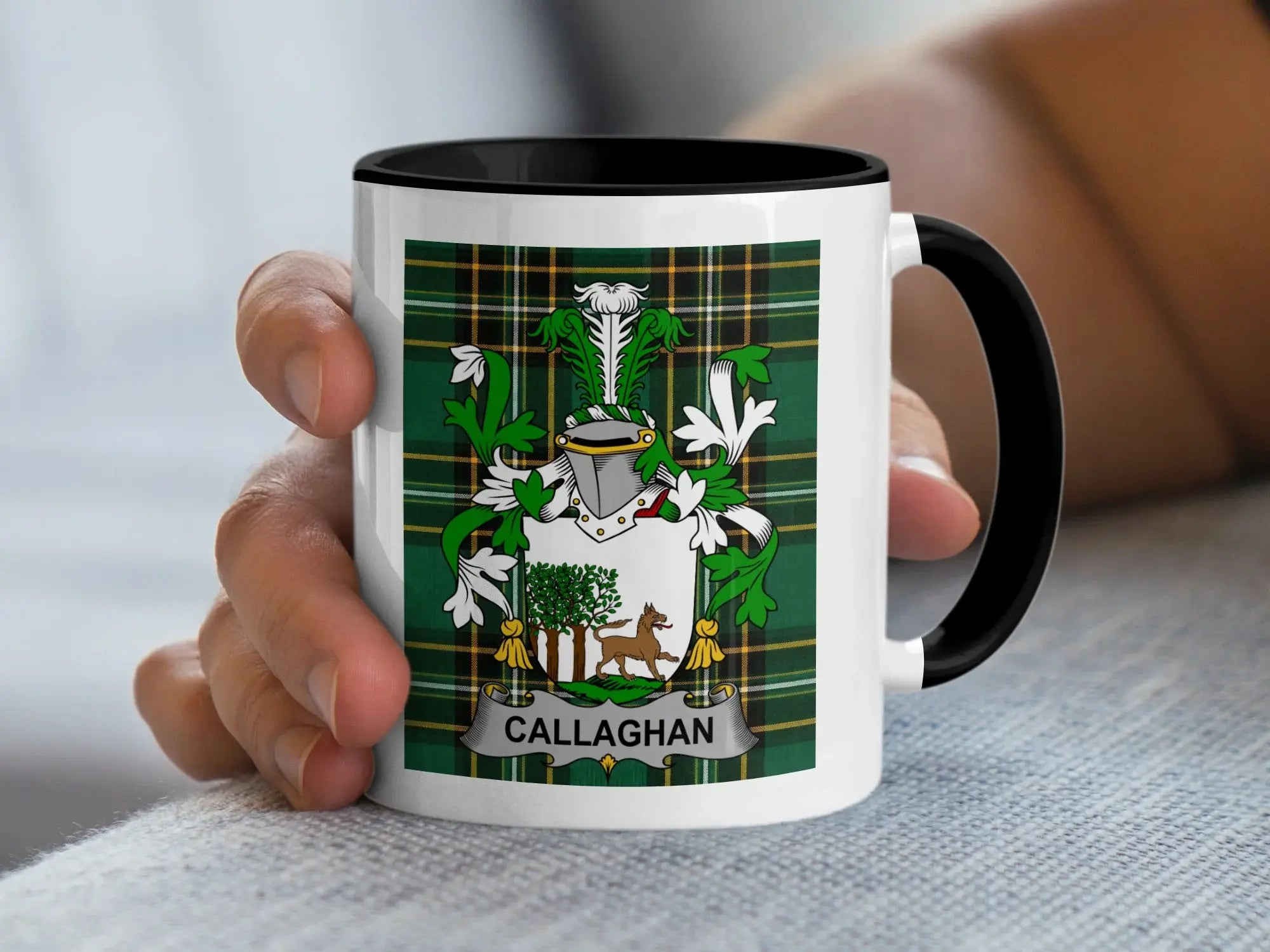 Callaghan coat of arms on a black and white ceramic mug held by a hand.