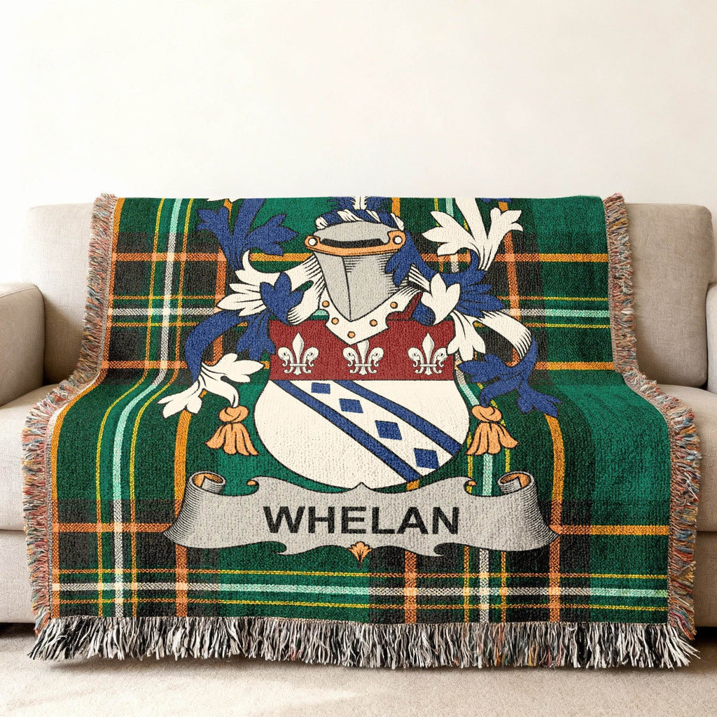 Green plaid woven throw blanket with Whelan family crest on couch.