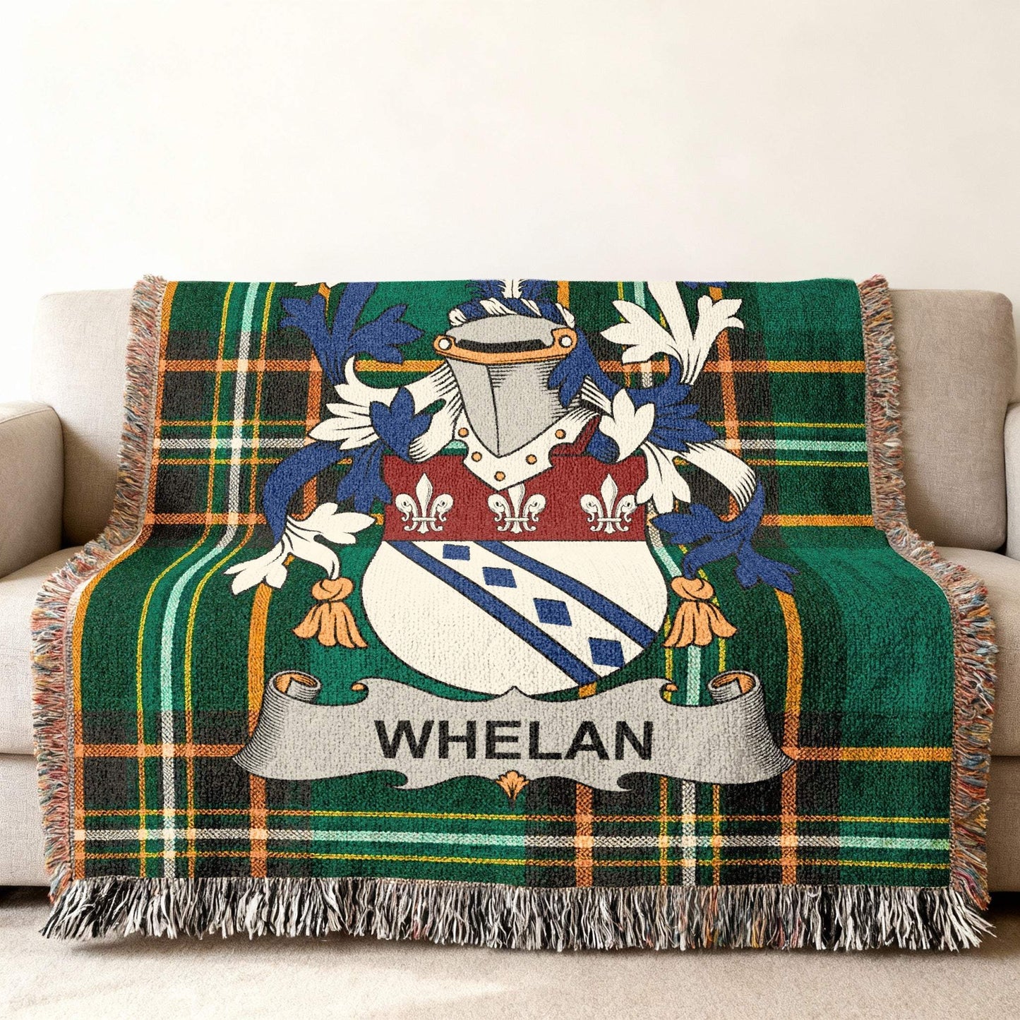 Green plaid woven throw blanket with Whelan family crest on couch.