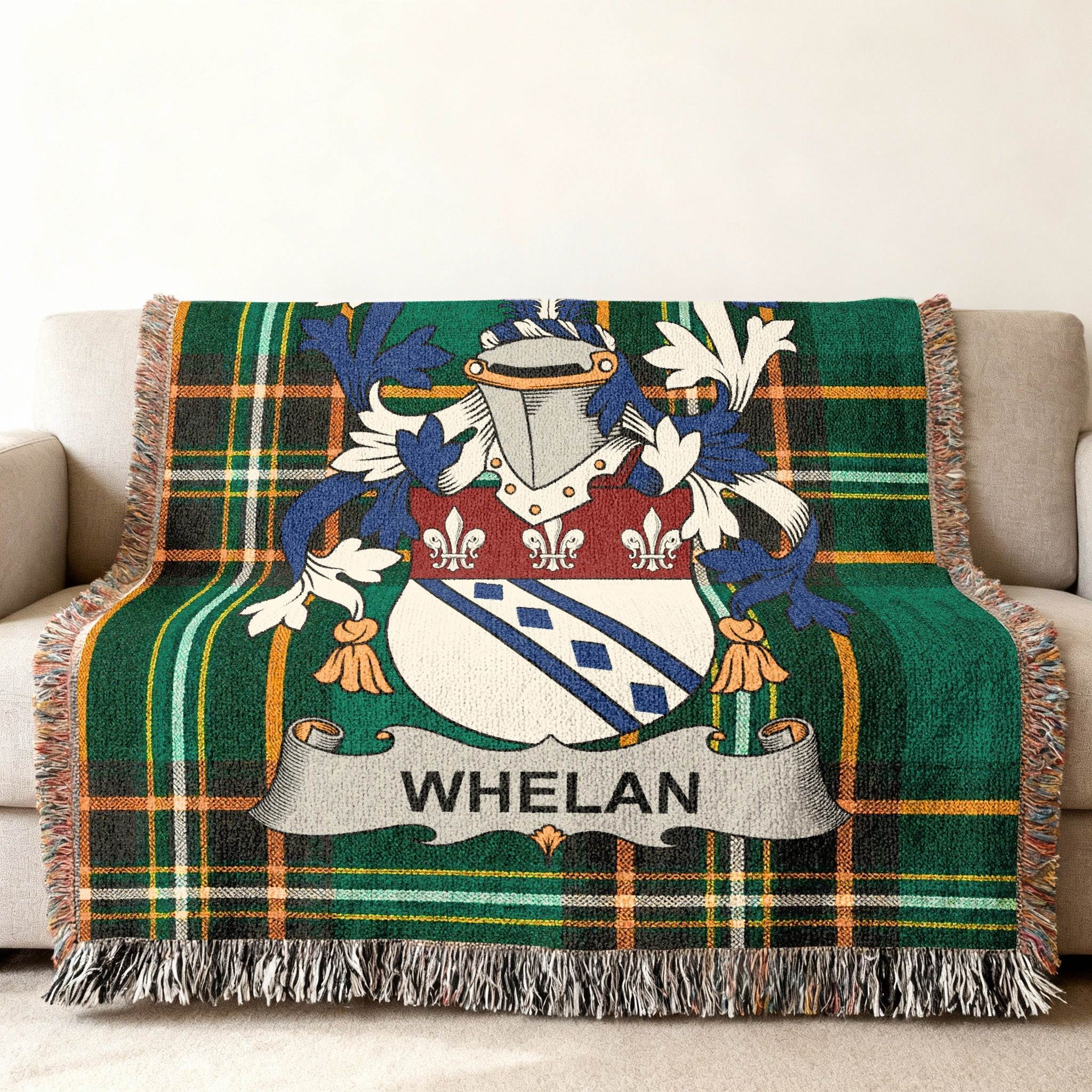 Green plaid woven throw blanket with Whelan family crest on couch.