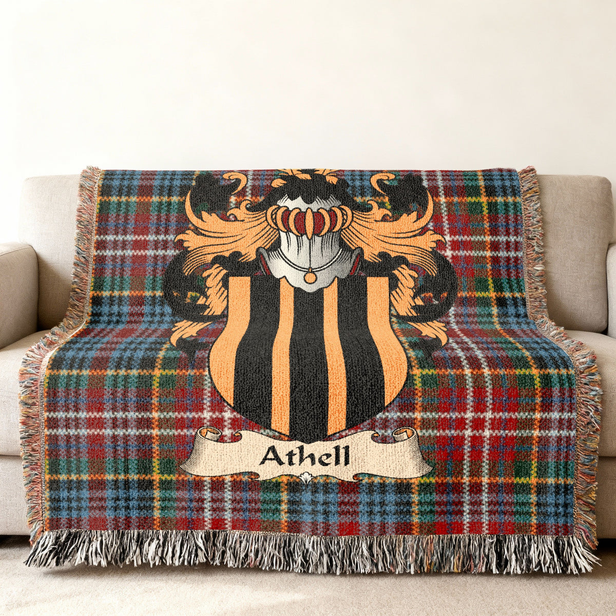Athell Scottish family shield woven blanket with Caledonia tartan background on a sofa