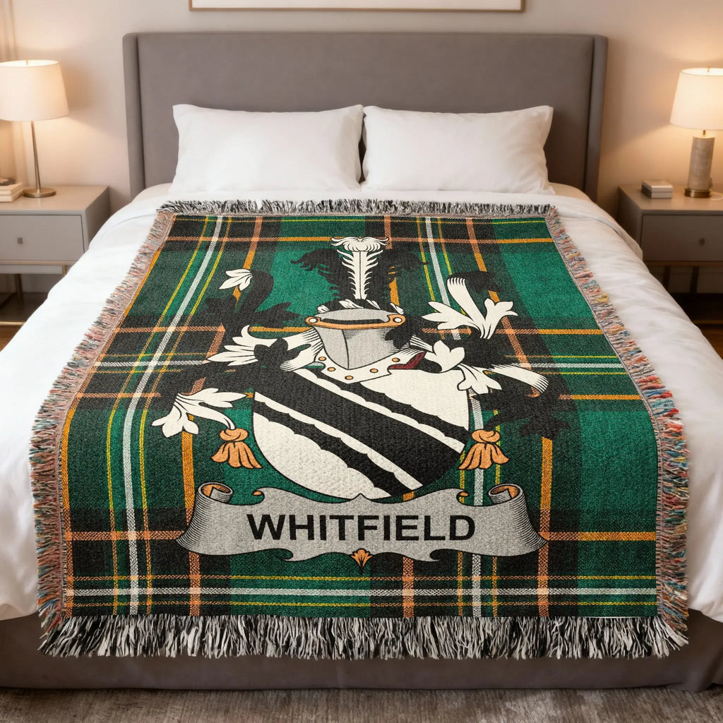 Tartan blanket with Whitfield family crest on a bed.