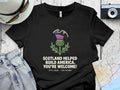 Black t-shirt with thistle graphic and "Scotland Helped Build America. You're Welcome!"