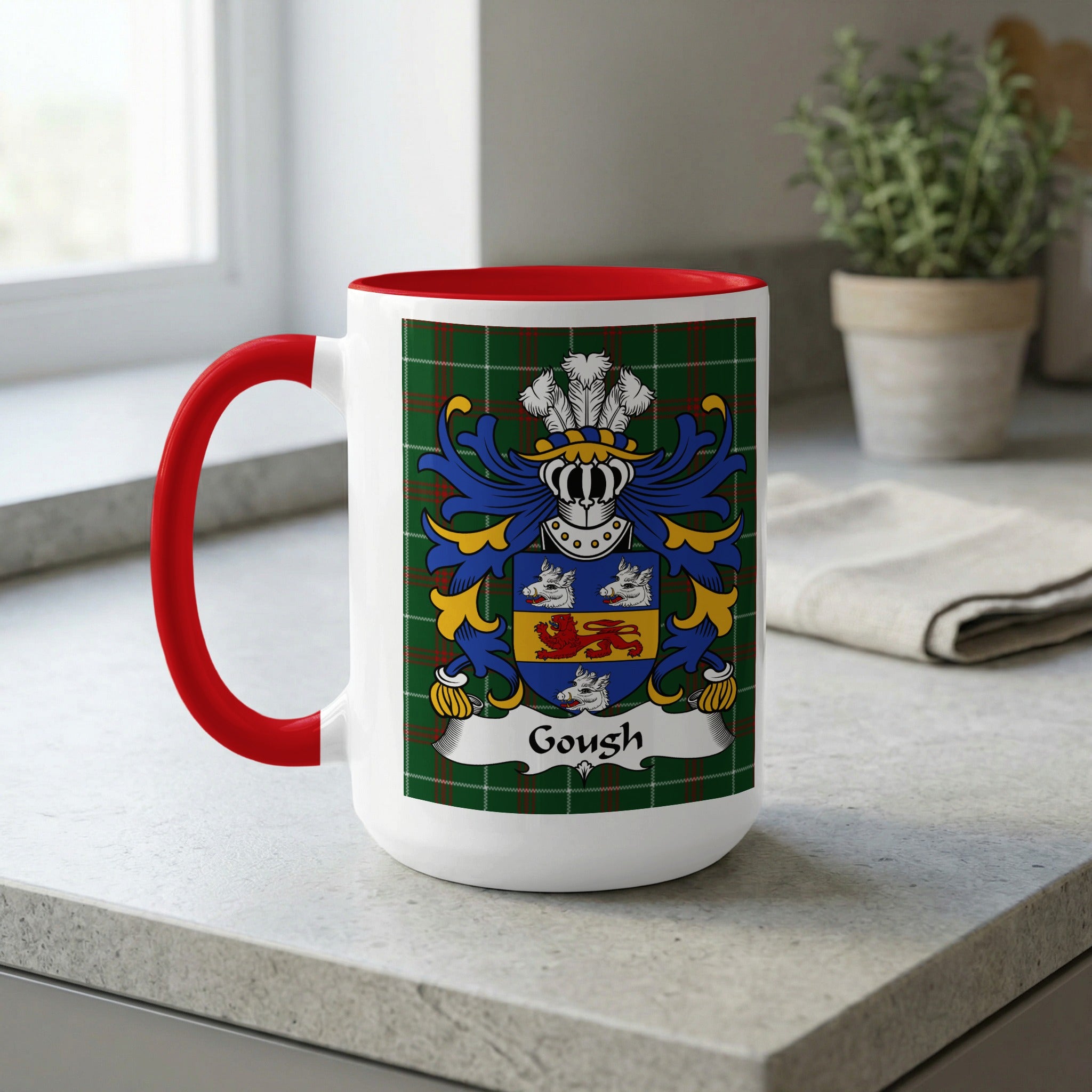 White mug with red handle and interior, displaying the Gough family crest on a tartan background.