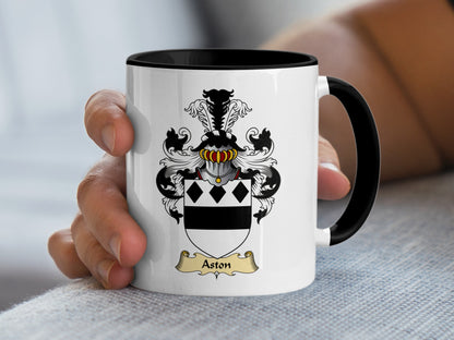 White mug with black rim, featuring the Aston family crest and name.