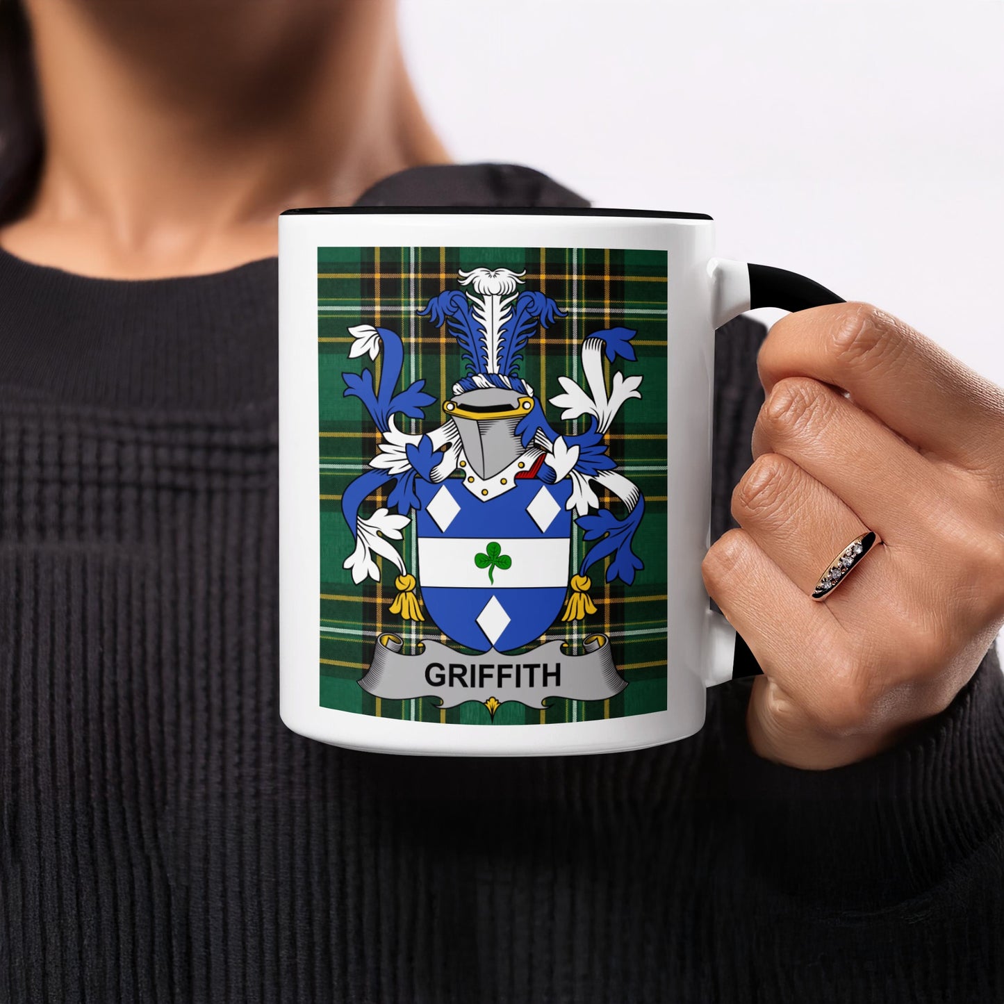Mug with Griffith family crest on tartan background held by a person.