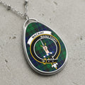 Oval pendant necklace with Mackay clan crest on green and blue plaid background