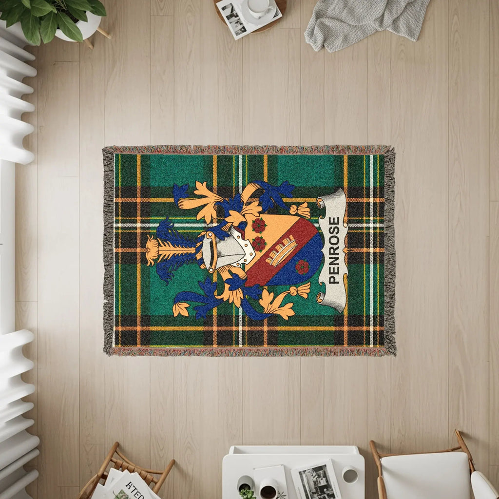 Woven blanket with Penrose family crest on green plaid background.