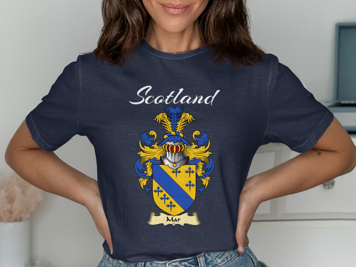 Model wearing a navy Mar T-shirt featuring a gold shield crossed by a blue diagonal band