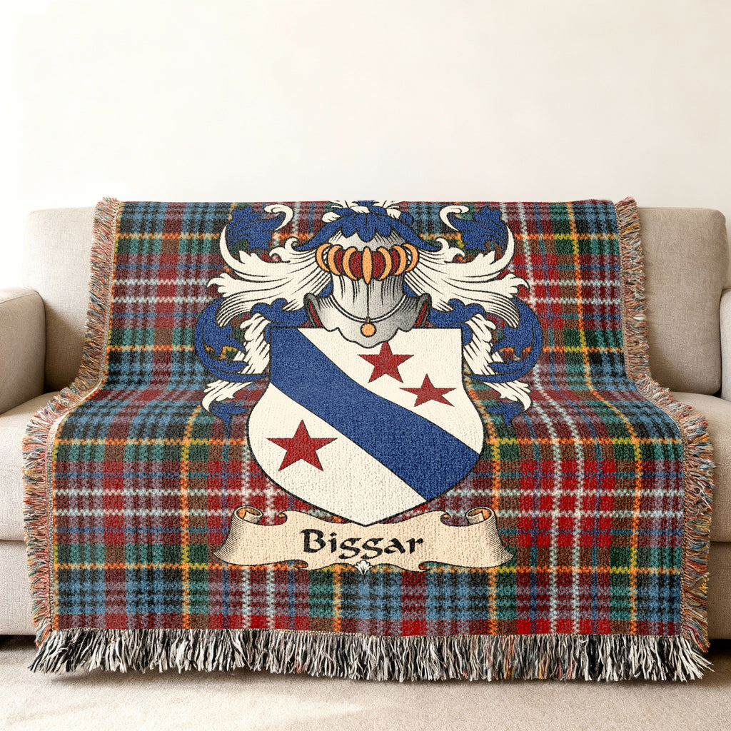 Biggar Scottish family shield woven blanket with Caledonia tartan background on a sofa
