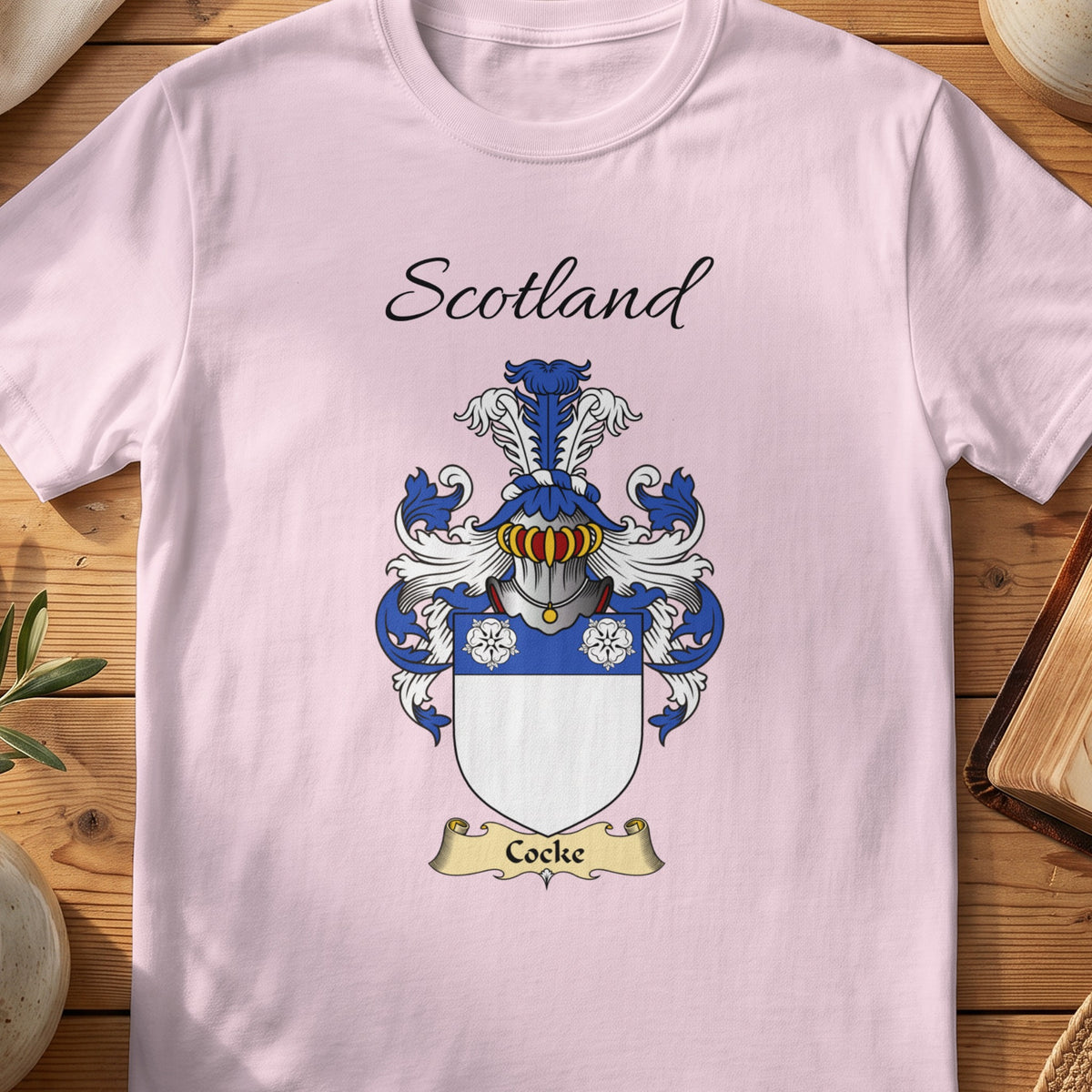 Light Pink Cocke Scottish family shield T-shirt featuring three white flowers on a blue band