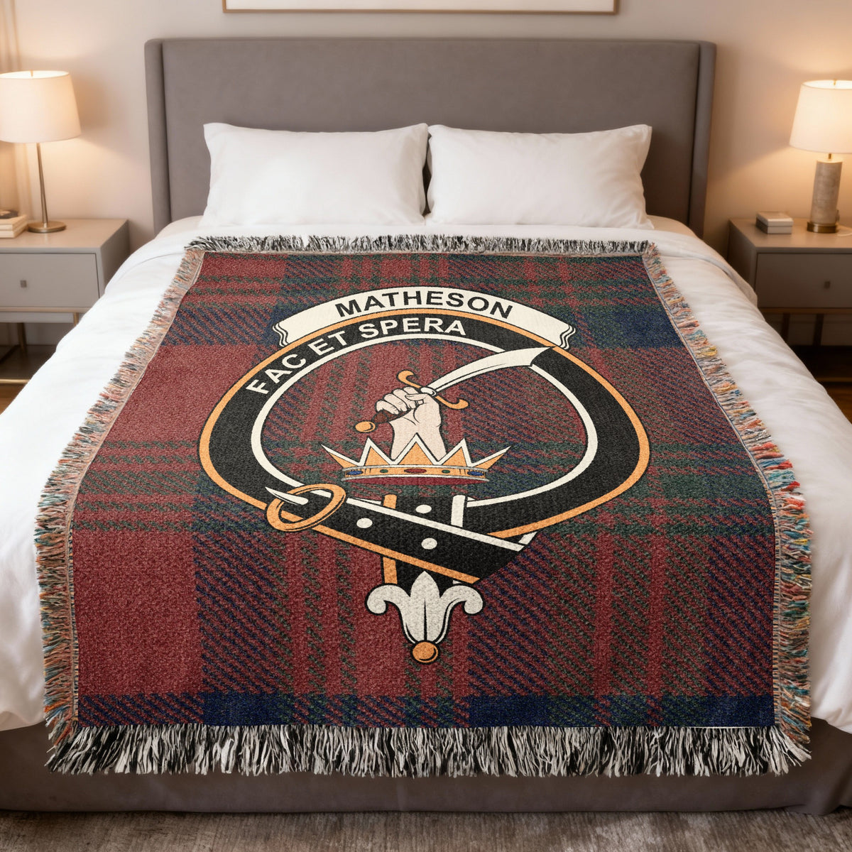 Matheson woven blanket displayed on a bed, with a hand holding a curved sword above a crown on a red and dark green tartan background